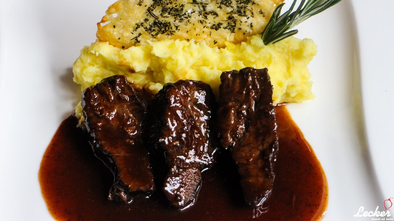 Geschmorte Kalbsbäckchen in Rosmarin-Mosto Cotto-Jus, Kartoffelpüree und Parmesan-Rosmarin-Ecken